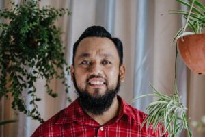 portrait of an Asian bearded man with hanging indoor plants