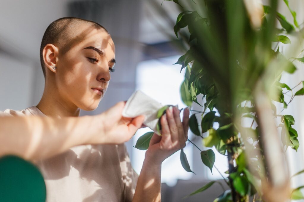 Young woman with cancer taking care of plants in her apartment.